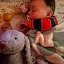 baby, sleeping, pacifier, blanket, plush_toy, stuffed_animal, rattle, bedspread, infant, cozy, child, cute, resting, soft_toy, toddler, indoor, comfort, peaceful, face, hand