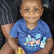 Haysen is registered to the contest to win money with this photo: toddler, child, smiling, blue_tshirt, orange_shorts, car_seat, inside_car, pacifier, snack, hands, legs, curly_hair, person, seat, window, daylight, vehicle, happy, casual_clothing, portrait