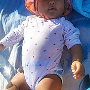 Mariama participe au concours pour gagner de l'argent avec cette photo : arm, baby, child, closeup, cute, daylight, face, hand, hat, infant, legs, lying_down, onesie, outdoor, relaxation, skin, summer, sunhat, sunlight, towel