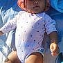arm, baby, child, closeup, cute, daylight, face, hand, hat, infant, legs, lying_down, onesie, outdoor, relaxation, skin, summer, sunhat, sunlight, towel