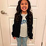 Jadiah is registered to the contest to win money with this photo: child, girl, smiling, standing, indoor, door, black_cardigan, gray_shirt, blue_butterflies, jeans, long_hair, curly_hair, happy, toothy_grin, wooden_floor, casual_clothing, portrait, person, home, fashion