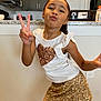 Jadiah joined the competition — help win amazing prizes! child, girl, pose, peace_sign, indoor, kitchen, white_top, sequin_heart, gold_skirt, sparkly, smiling, playful, person, fashion, casual, hair_tied_back, wall, floor, appliance, countertop
