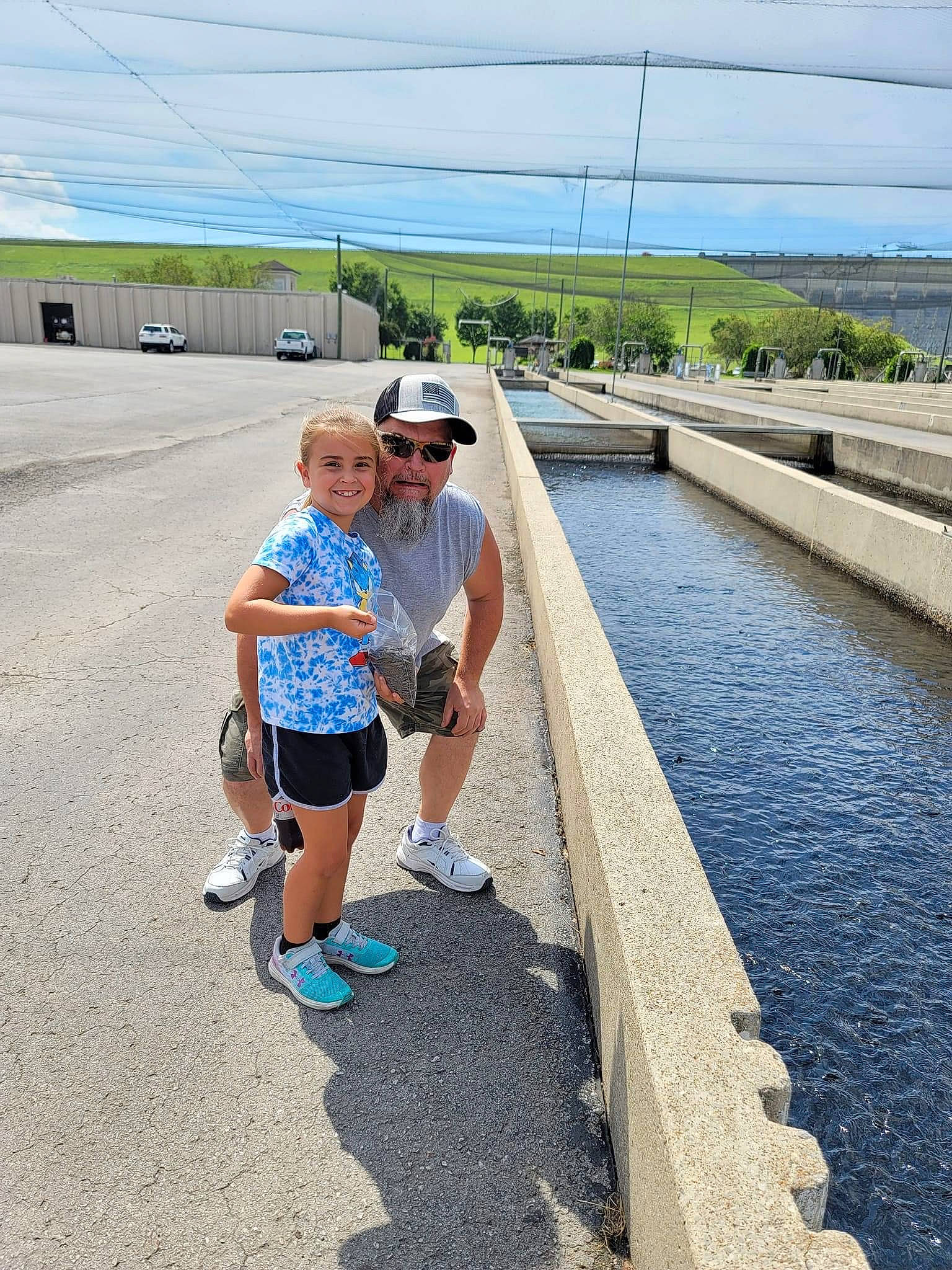 Paisley is registered to the contest to win money with this photo: asphalt, eyewear, footwear, fun, hat, headwear, joy, landscape, leisure, nonbuilding_structure, pedestrian, person, recreation, reservoir, road, shorts, sky, toddler, tourism, travel