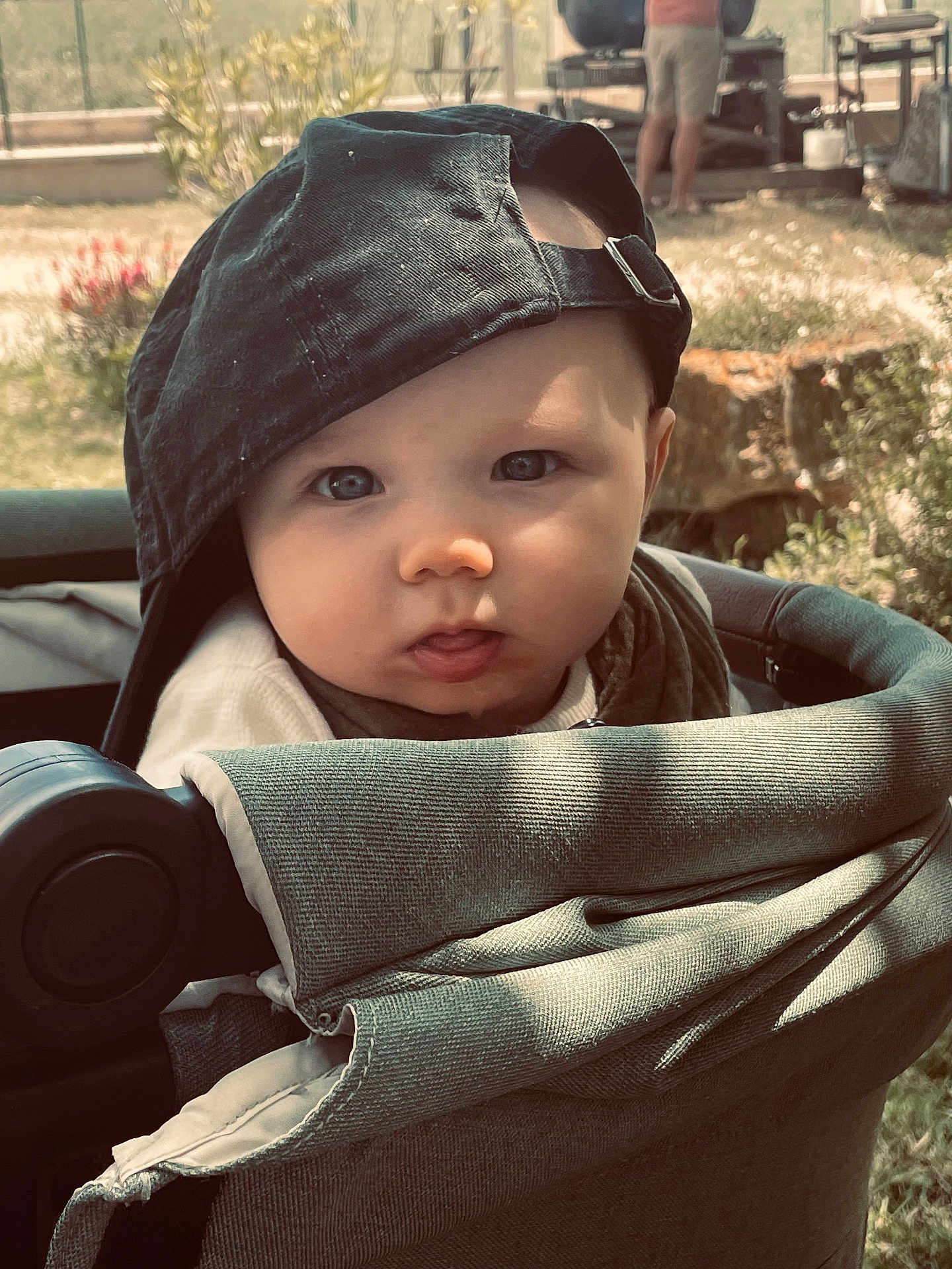 Léïo a rejoint le concours — aidez-le/la à gagner de superbes lots ! baby, child, stroller, cap, hat, face, outdoor, garden, curious, infant, portrait, cute, young, person, sunlight, nature, greenery, soft_light, closeup, expression