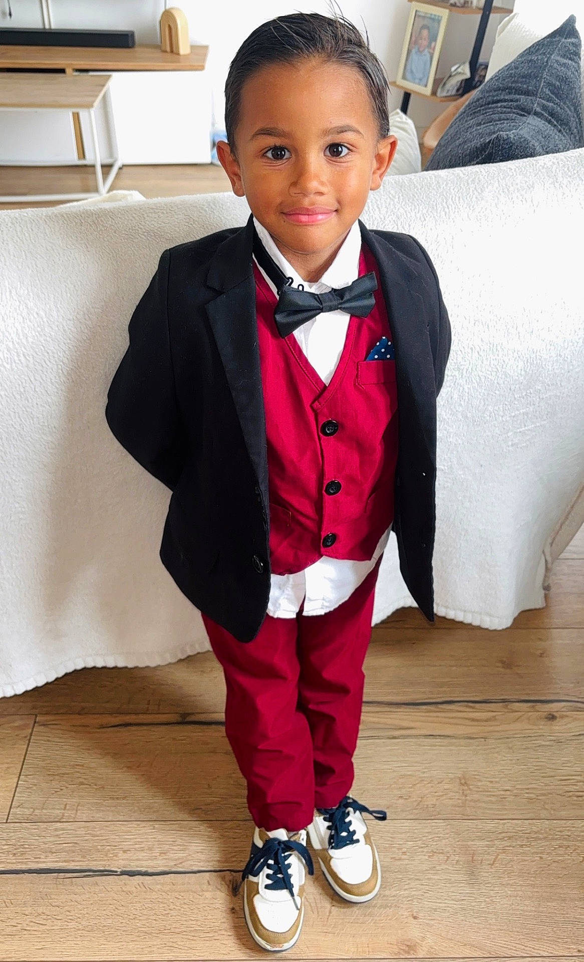 Selyan a rejoint le concours — aidez-le/la à gagner de superbes lots ! black_blazer, bow_tie, boy, child, confident, couch, fashion, formal_wear, framed_photo, home, indoor, person, portrait, red_suit, smiling, sneakers, standing, white_shirt, wooden_floor, young
