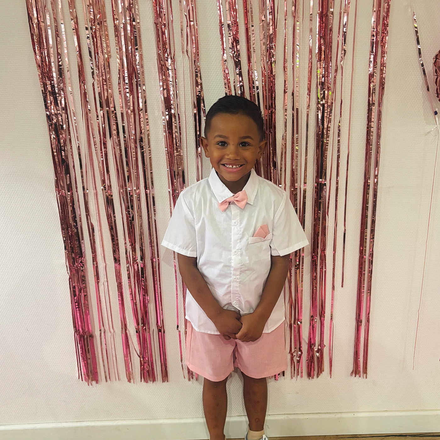 Selyan participe au concours pour gagner de l'argent avec cette photo : child, boy, smile, happy, standing, indoor, party, decoration, fringe_curtain, pink, white_shirt, bow_tie, shorts, sneakers, wooden_floor, wall, fashion, portrait, celebration, cute