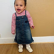 Laïa a rejoint le concours — aidez-le/la à gagner de superbes lots ! child, toddler, baby, smile, laughing, face, hair_bow, bow, denim_dress, dress, floral_top, white_shoes, ribbon, socks, wooden_floor, textured_wall, baseboard, standing, cute, happy