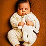 baby, sleeping, stuffed_animal, bunny, knitwear, cozy, brown_background, infant, cute, child, soft_texture, peaceful, hands, feet, portrait, indoors, warm_colors, plush_toy, toddler, resting