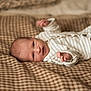 baby, infant, newborn, striped_onesie, blanket, checkered, soft_texture, lying_down, curious, hands, face, portrait, cozy, warm, indoor, closeup, cute, comfort, sleepwear, resting