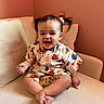 Erica joined the competition — help win amazing prizes! baby, child, colorful_clothing, couch, cozy, cross_legged, cute, face, happy, homedecor, indoor, infant, light, patterned_outfit, person, pigtails, portrait, sitting, smiling, wall