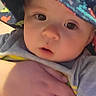 Hudson joined the competition — help win amazing prizes! baby, child, infant, portrait, face, eyes, looking_at_camera, bucket_hat, hat, colorful_clothing, gray_shirt, being_held, adult_hand, close_up, indoor, soft_lighting, adorable, curious, vertical_photo, family