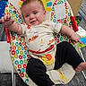 baby, infant, child, smiling, sitting, bouncer, chair, portrait, indoors, playroom, colorful, toy, cushion, patterned, clothing, elephant_print, reaching, happy, carpet, family