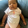 baby, blue_cushion, child, chubby_cheeks, comfortable, curious_expression, cushion, cute, hand, ice_cream_embroidery, indoors, infant, legs, onesie, pink_clothing, portrait, relaxed, seated, skin, soft_light