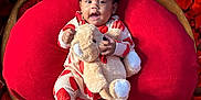 Jordan is registered to the contest to win money with this photo: baby, child, teddy_bear, red_cushion, wooden_bowl, rose_petals, heart_pattern, pajamas, smiling, cute, indoor, plush_toy, portrait, cozy, comfort, infant, relaxing, soft_texture, bright_colors, adorable