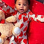 Jordan is registered to the contest to win money with this photo: baby, toddler, heart_pattern, pajamas, teddy_bear, red_cushion, wood_floor, child, cute, smiling, indoor, plush_toy, cozy, happy, infant, portrait, lying_down, clothing, warm, adorable