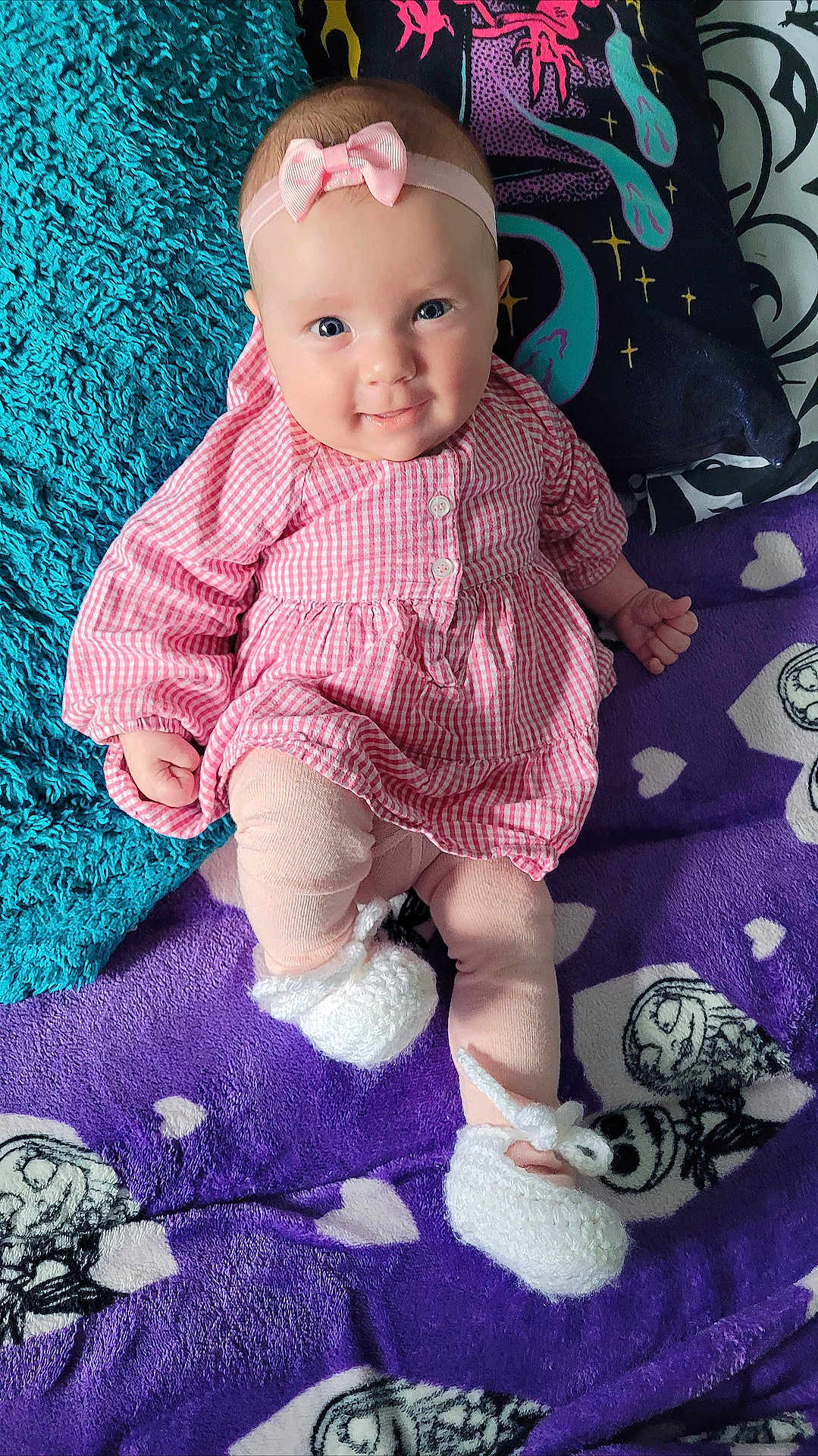 Maeve joined the competition — help win amazing prizes! baby, child, smiling, pink_dress, headband, bow, blanket, pillow, purple_blanket, white_booties, cozy, indoor, cute, infant, lying_down, patterned_blanket, soft_texture, happy, person, portrait