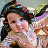 baby, child, infant, pajamas, colorful_bonnet, face, wide_eyes, tattoos, hand, indoors, bed, blanket, cute, expression, person, clothing, skin, young, portrait, sitting