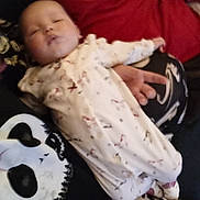 Roselyne is registered to the contest to win money with this photo: baby, black_shirt, blur, casual, clothing, comfort, couch, cute, hand, indoors, infant, pajamas, person, pillow, red_pillow, relaxation, resting, skull_design, sleeping, soft_lighting