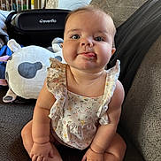 Harper joined the competition — help win amazing prizes! baby, child, infant, sitting, tongue_out, cute, plush_toy, couch, home_interior, clothing, person, face, baby_car_seat, soft_toys, comfort, smiling, ruffled_clothes, indoors, young_child, playful