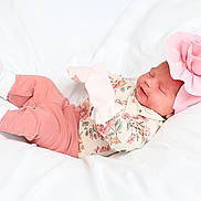 Everlee is registered to the contest to win money with this photo: baby, newborn, infant, sleeping, flower_headband, pink_clothing, floral_pattern, white_blanket, soft_texture, cute, cozy, child, portrait, resting, indoors, small, adorable, peaceful, laying_down, headwear