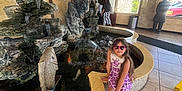 Nathaly joined the competition — help win amazing prizes! child, door, entrance, fish_statue, floor_tiles, girl, handbag, indoor, lighting, people, plant, purple_dress, reflection, rocks, shoes, statue, sunglasses, water, water_feature, window