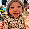 baby, beanie, cheerful, child, clothing, cute, expression, face, floral, happy, hat, headwear, indoor, pattern, person, portrait, sitting, smiling, toddler, young