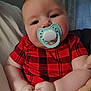 Carter is registered to the contest to win money with this photo: baby, pacifier, red_shirt, plaid, chubby_cheeks, indoor, hands, face, person, infant, cute, plush, portrait, curtains, clock, skin, sitting, holding, calm, child