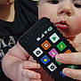 Carter joined the competition — help win amazing prizes! baby, child, toy_phone, hand, fingers, adult, black_shirt, face, closeup, indoor, curious, skin, holding, colorful, buttons, technology_toy, person, young_child, playing, focus
