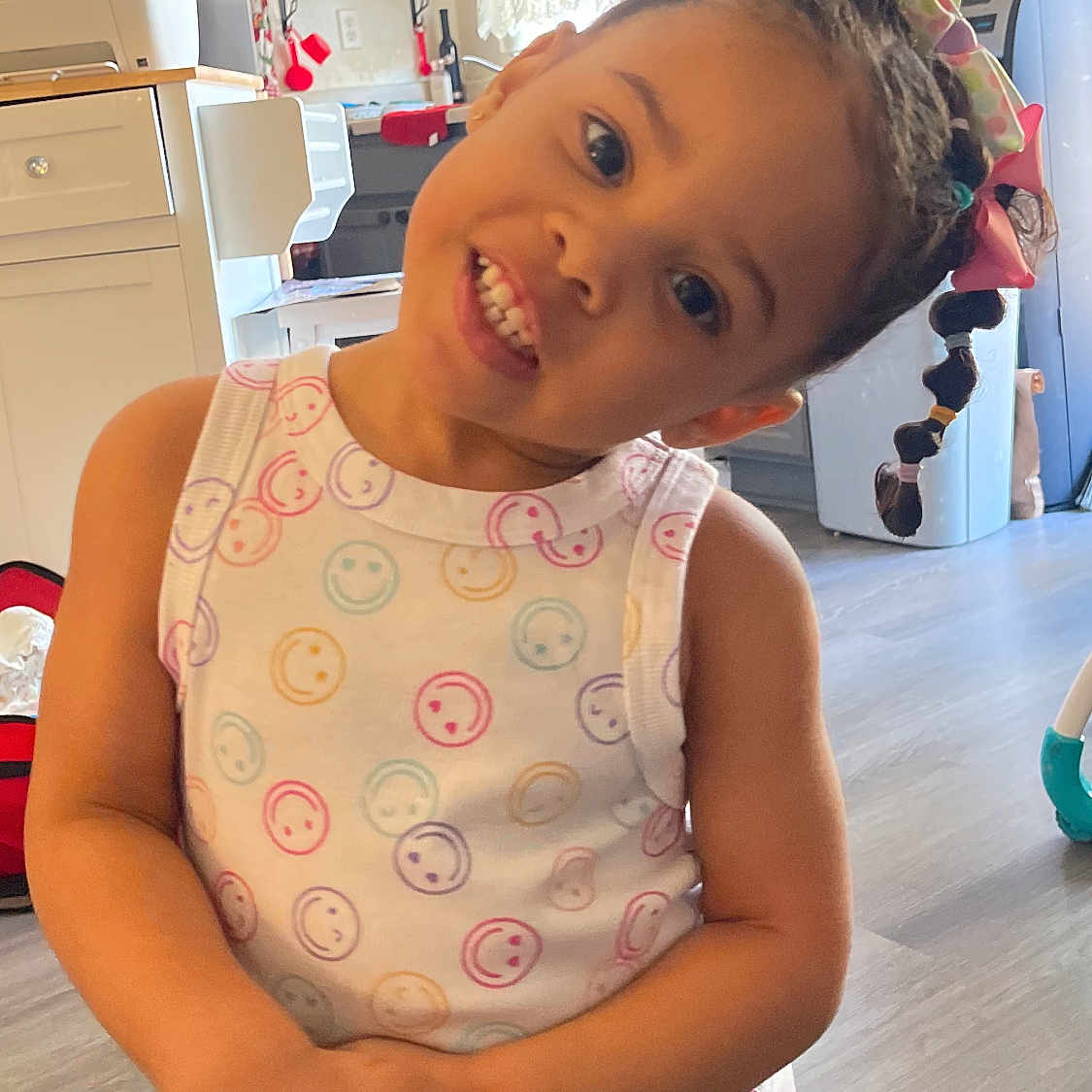 Ava joined the competition — help win amazing prizes! appliance, bows, braids, cabinet, child, clothing, colorful, cute, floor, girl, hair, happy, home, indoors, kitchen, person, playful, smiling, tank_top, young