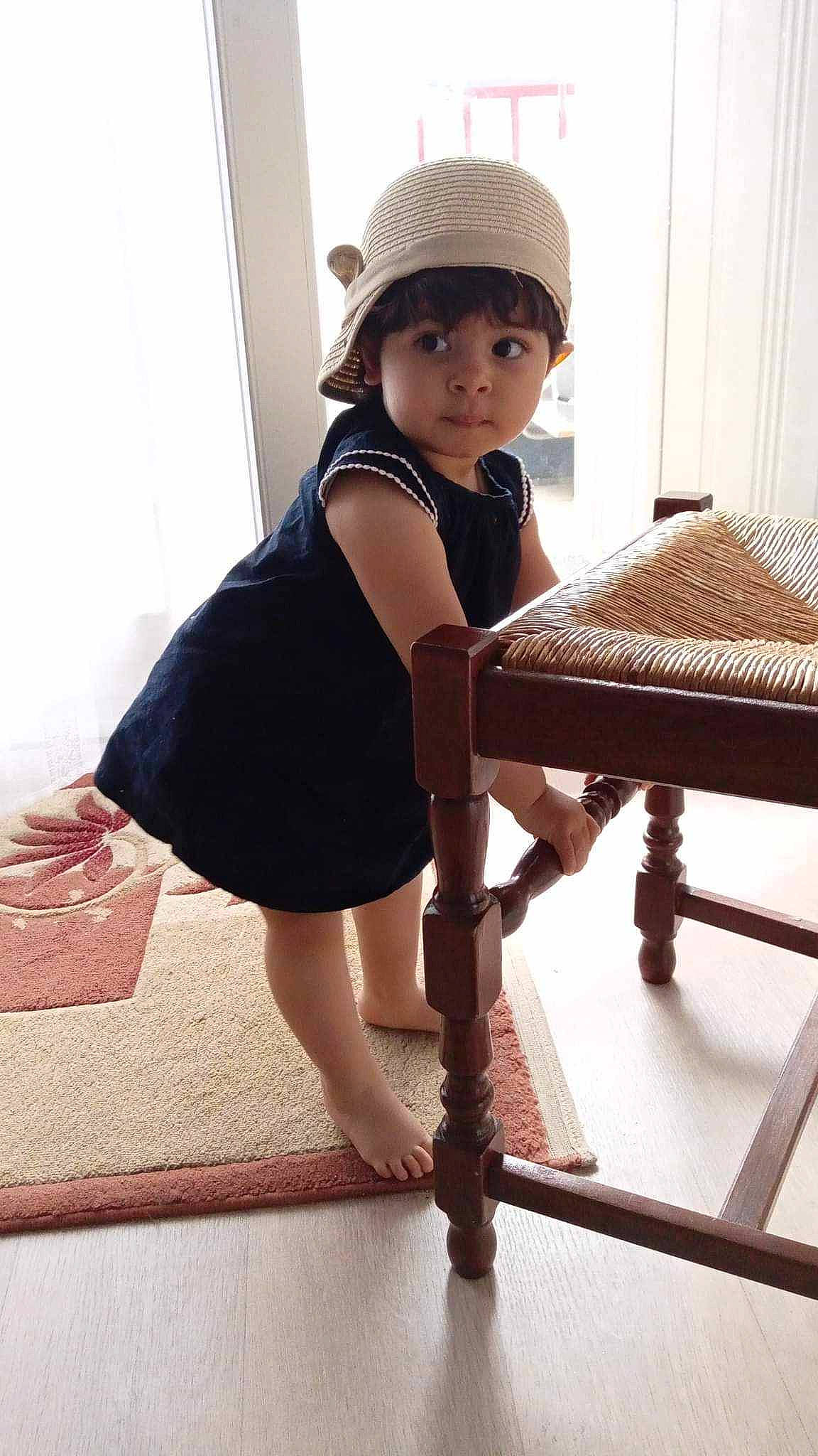 Selma participe au concours pour gagner de l'argent avec cette photo : baby_toddler_clothing, cap, day_dress, dress, flash_photography, floor, flooring, hat, headgear, knee, leg, one_piece_garment, person, shoe, shoulder, sleeve, stairs, standing, thigh, waist