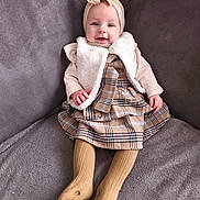 Joyce participe au concours pour gagner de l'argent avec cette photo : baby, infant, child, smiling, headband, bow, plaid_dress, fur_vest, tights, socks, hands, eyes, cheeks, sitting, sofa, blanket, cozy, portrait, fabric_texture, outfit