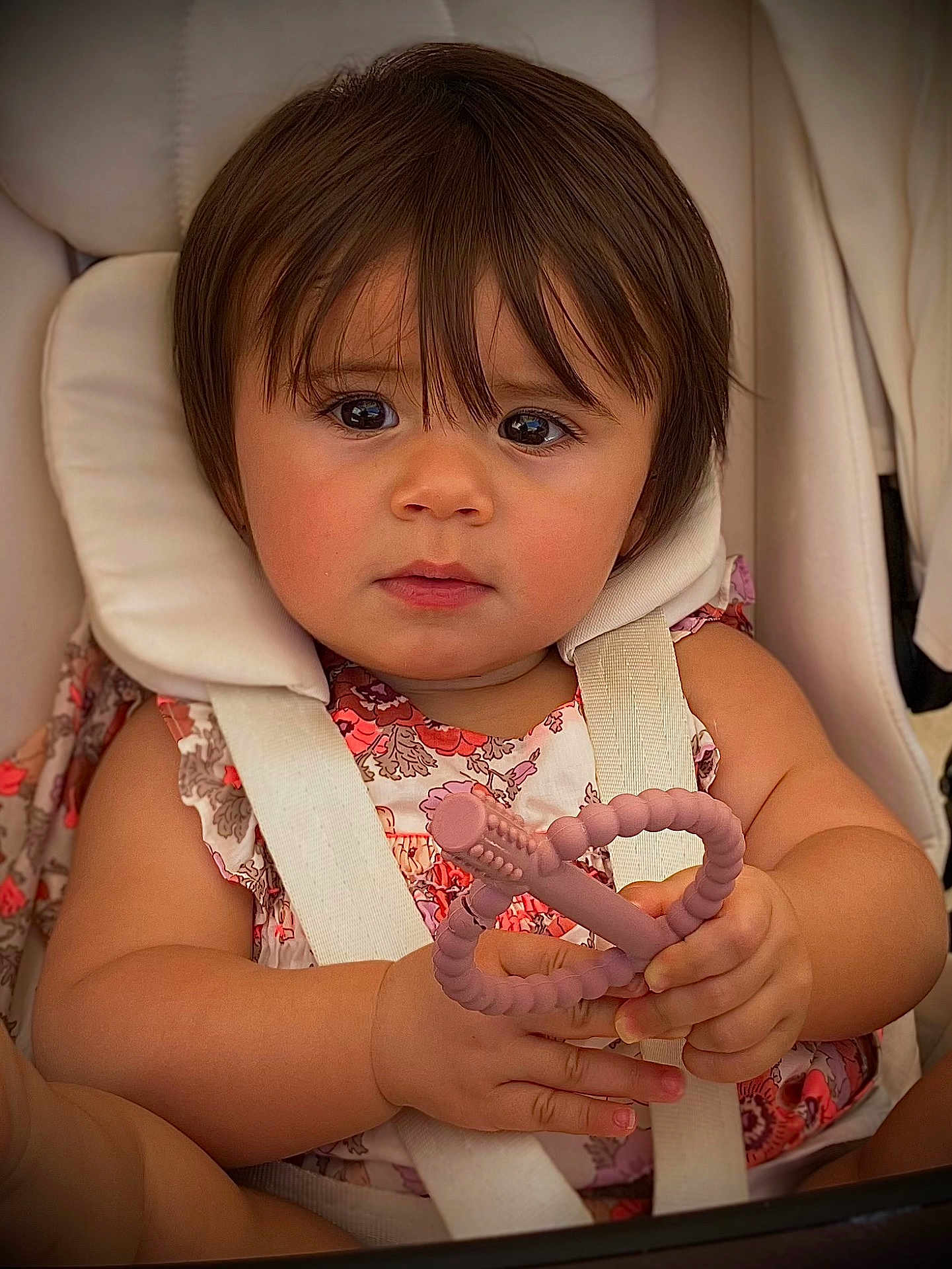 Julia a rejoint le concours — aidez-le/la à gagner de superbes lots ! toddler, child, baby, face, hands, teething_toy, stroller, seatbelt, floral_clothing, curly_hair, cute, indoors, closeup, skin, expression, young_child, sitting, comfort, play, infant