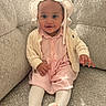 baby, cardigan, child, clothing, couch, cozy, cute, happy, hat, indoors, infant, person, pink_dress, portrait, seated, smiling, socks, sofa, textured_fabric, tights