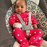 Emerie is registered to the contest to win money with this photo: baby, infant, polka_dot, pink_clothing, baby_seat, patterned_cushion, straps, sitting, indoor, child, cute, adorable, face, person, small_hands, footed_pajamas, soft_toys, comfort, young_child, portrait