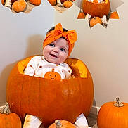 Mabel is registered to the contest to win money with this photo: baby, pumpkin, headband, pajamas, orange, smiling, sitting, carpet, wall, cute, child, holiday, halloween, decor, multiple_faces, expression, small_pumpkins, indoors, playful, festive