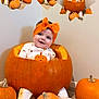 baby, pumpkin, headband, pajamas, orange, smiling, sitting, carpet, wall, cute, child, holiday, halloween, decor, multiple_faces, expression, small_pumpkins, indoors, playful, festive