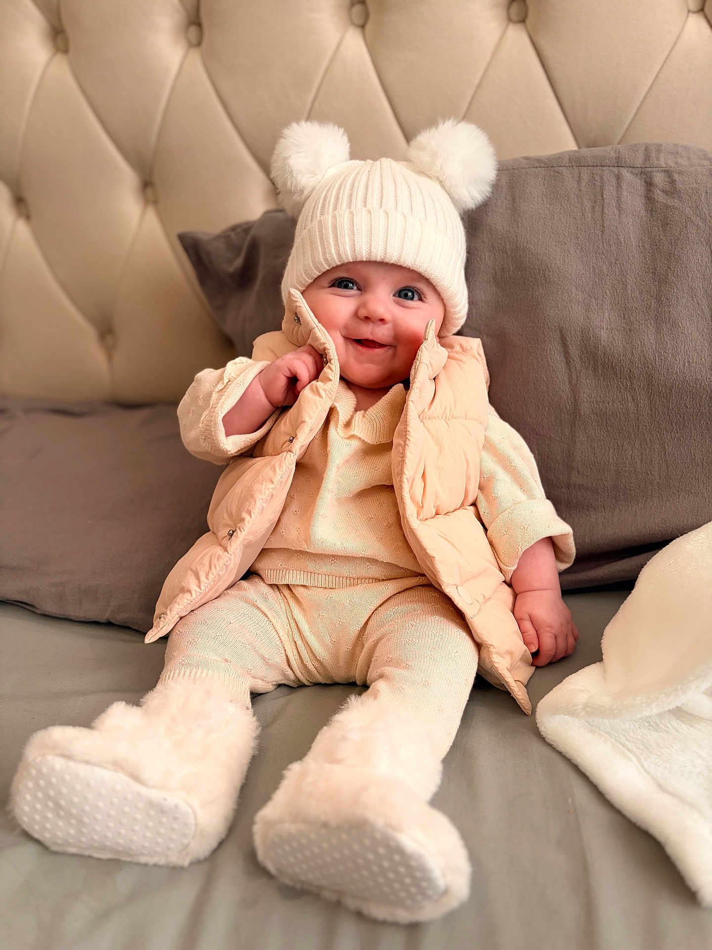 Mabel is registered to the contest to win money with this photo: baby, child, smiling, hat, knitwear, vest, boots, bed, pillow, blanket, cozy, cute, indoor, portrait, warm, happy, infant, fashion, soft, candid