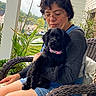 Perrita Gabby joined the competition — help win amazing prizes! woman, dog, puppy, black_dog, pink_collar, wicker_chair, outdoor, plants, greenery, suburban, glasses, shorts, long_sleeve_shirt, nature, relaxing, portrait, seated, cuddling, calm, daylight