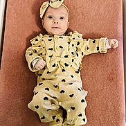 Ava participe au concours pour gagner de l'argent avec cette photo : baby, infant, onesie, headband, bow, heart_pattern, changing_pad, mattress, pink_background, cute, portrait, lying_down, hands, feet, ruffles, buttons, newborn, eyes, clothing, smile