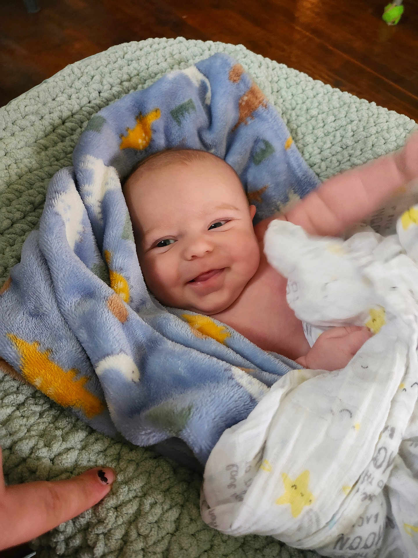 Peyton joined the competition — help win amazing prizes! baby, blanket, smiling, infant, face, hand, nail_polish, blue_blanket, patterned_blanket, soft_texture, green_surface, wrapped, cute, child, skin, happy, indoors, closeup, person, toddler