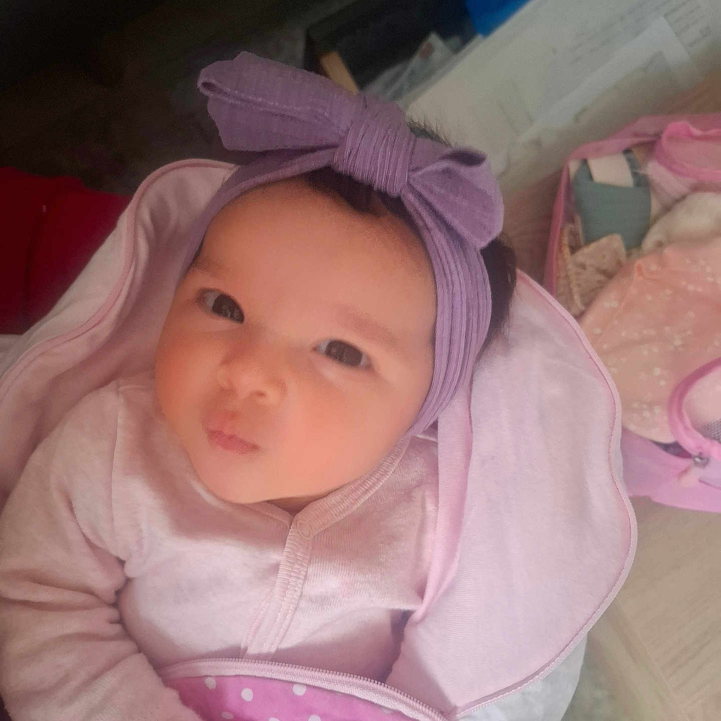 Léya participe au concours pour gagner de l'argent avec cette photo : baby, infant, headband, bow, blanket, pink, purple, clothing, indoors, cute, face, portrait, child, newborn, soft, wrapped, person, baby_accessories, pout, curious