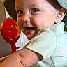 Gage is registered to the contest to win money with this photo: baby, child, smiling, hat, green_hat, baby_seat, toy, red_toy, animal_print, indoor, portrait, happy, cute, infant, toddler, clothing, face, seat, colorful, playtime