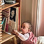 baby, biting, book_spines, books, casual, child, cozy, crawling, curious, expression, floor, furniture, home, indoor, leg, natural_light, person, pink_outfit, records, wooden_shelf