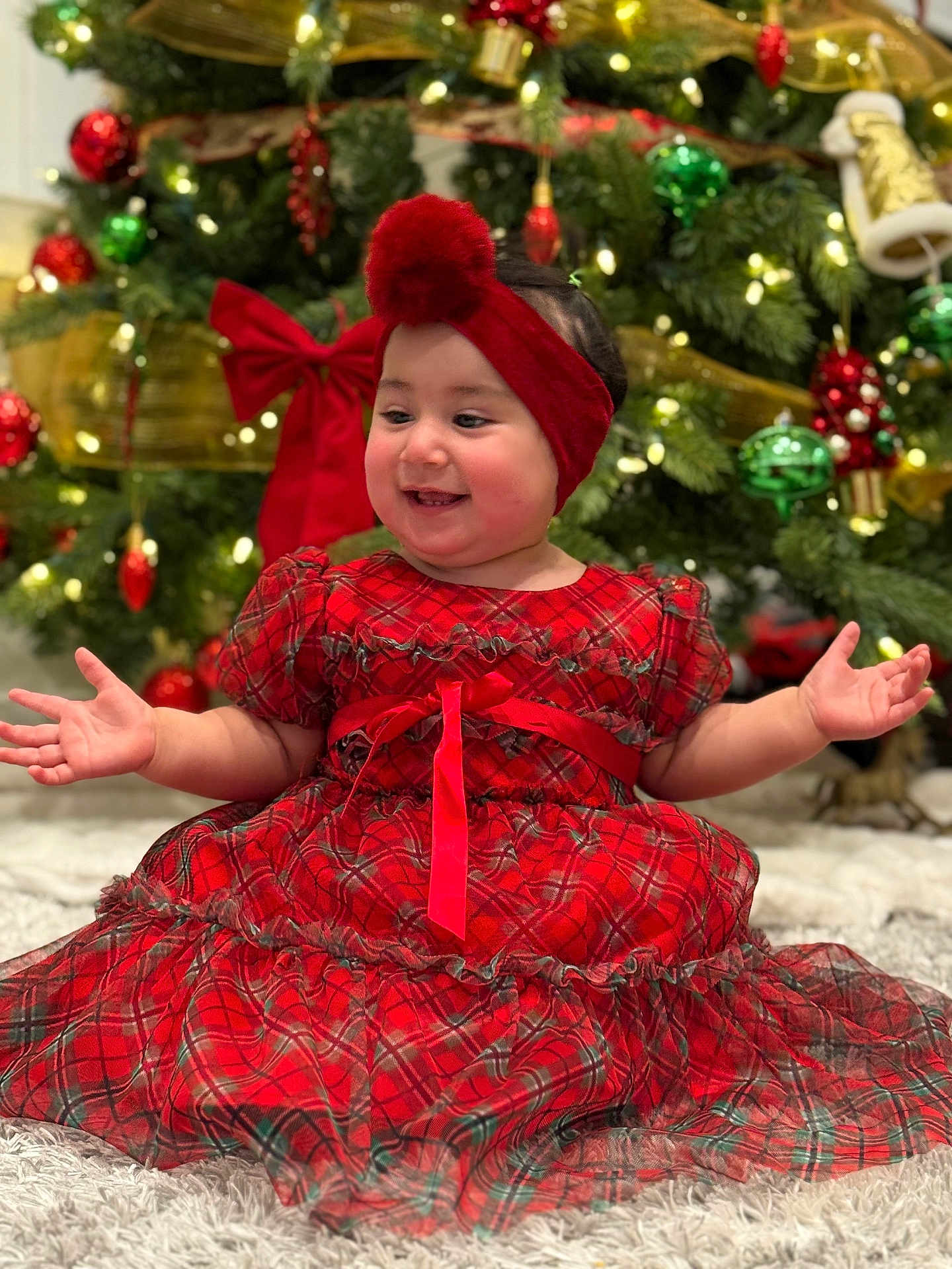 Raizel joined the competition — help win amazing prizes! baby, child, red_dress, headband, pom_pom, christmas_tree, ornaments, lights, holiday, festive, smiling, carpet, indoor, happy, celebration, toddler, holiday_decor, seasonal, portrait, cute