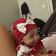 Nalani joined the competition — help win amazing prizes! baby, infant, smile, red_hat, bow, floral_outfit, hand, indoor, person, child, furniture, backpack, wall, door, bed, happy, clothing, headwear, skin, portrait