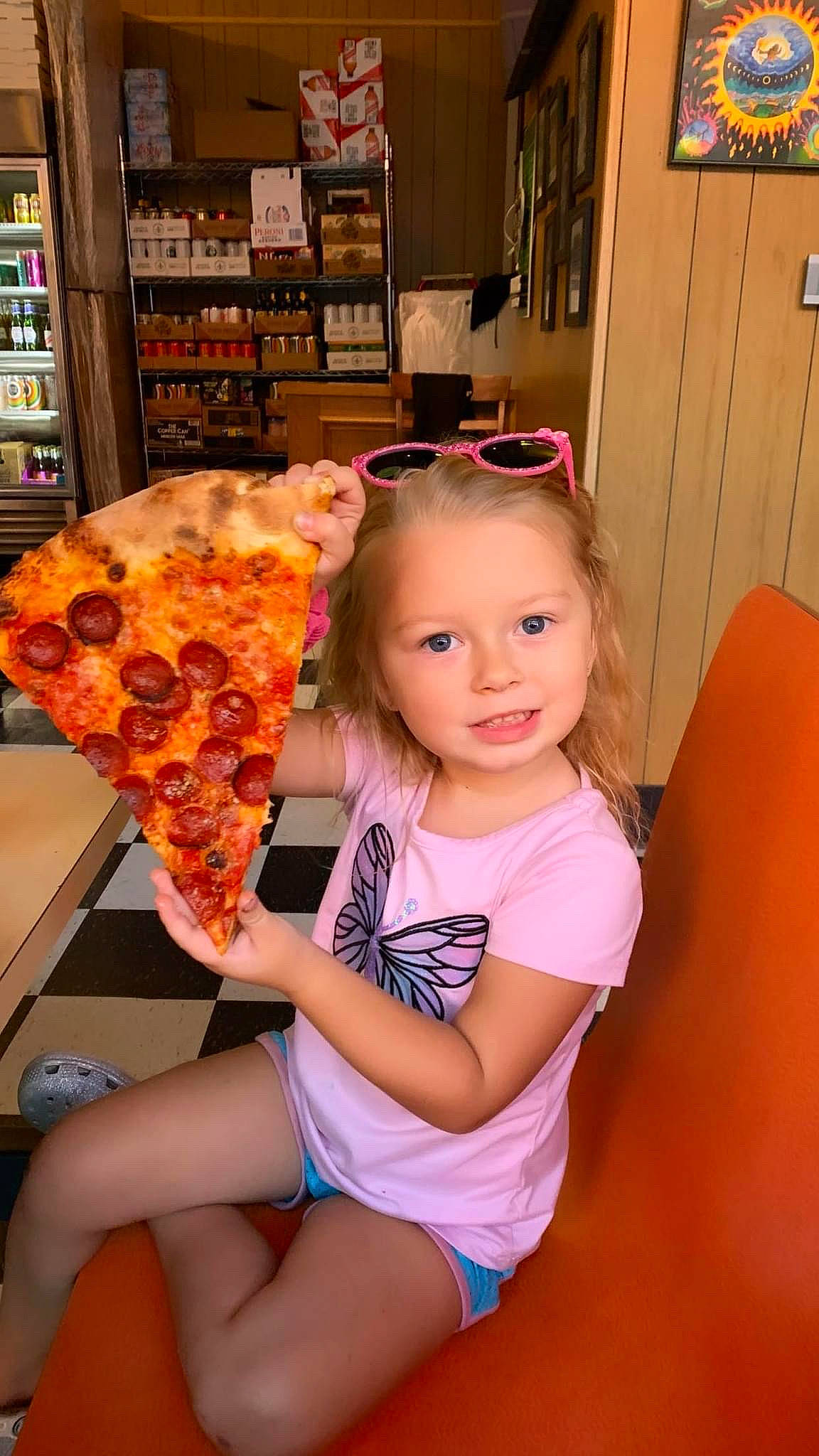 Hendrix is registered to the contest to win money with this photo: blond, chair, child, dress, eyewear, food, fun, happy, human_leg, ingredient, joy, junk_food, leisure, orange, person, pink, shelf, shelving, sunglasses, tableware