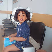 Myra a rejoint le concours — aidez-le/la à gagner de superbes lots ! child, girl, curly_hair, white_hat, waiting_room, book, purse, chair, polka_dot_dress, socks, white_shoes, wooden_floor, wall_art, empty_chairs, indoor, portrait, sitting, curious, person, casual