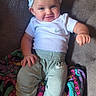 Davina is registered to the contest to win money with this photo: baby, child, infant, smiling, portrait, indoor, sitting, couch, bow, headband, white_shirt, sporty_clothing, pants, shoes, blanket, colorful, cozy, happy, face, nike