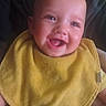 baby, smile, yellow_bib, yellow_onesie, happy, infant, face, child, portrait, cute, sitting, indoor, soft_light, expression, young_child, clothing, person, skin, head, baby_bib