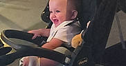 Davina joined the competition — help win amazing prizes! baby, child, infant, stroller, smiling, happy, sitting, indoor, portrait, candid, white_shirt, baby_socks, black_stroller, harness, seat, wheel, floor, chair, joyful, family